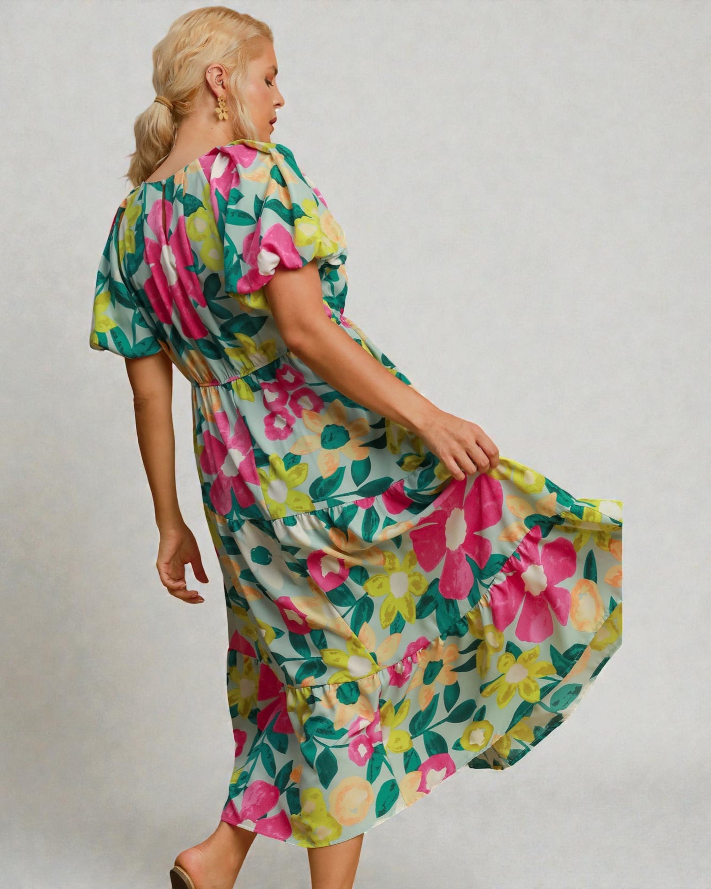 Woman wearing a colorful floral dress against a plain background