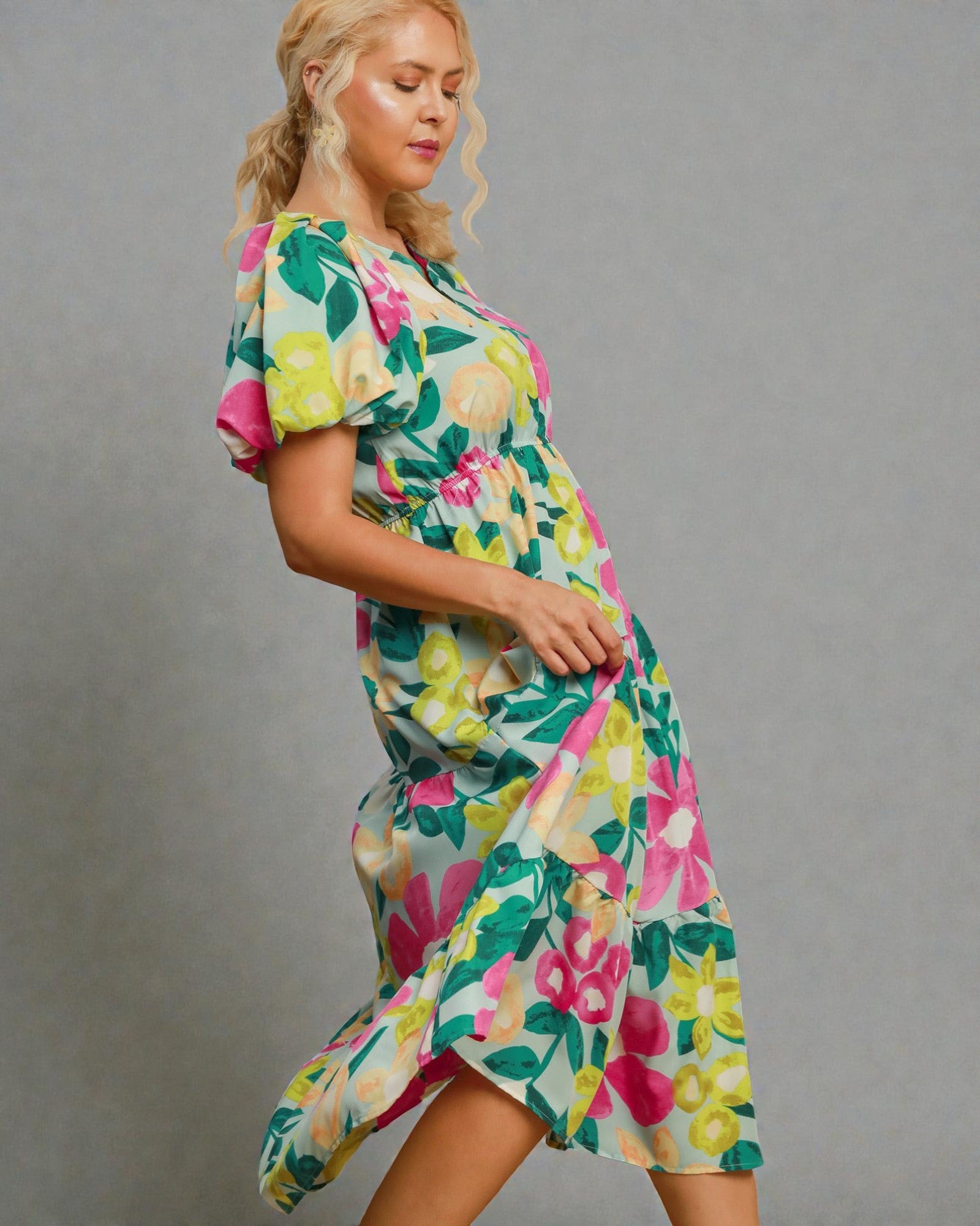 Woman wearing a colorful floral dress against a gray background