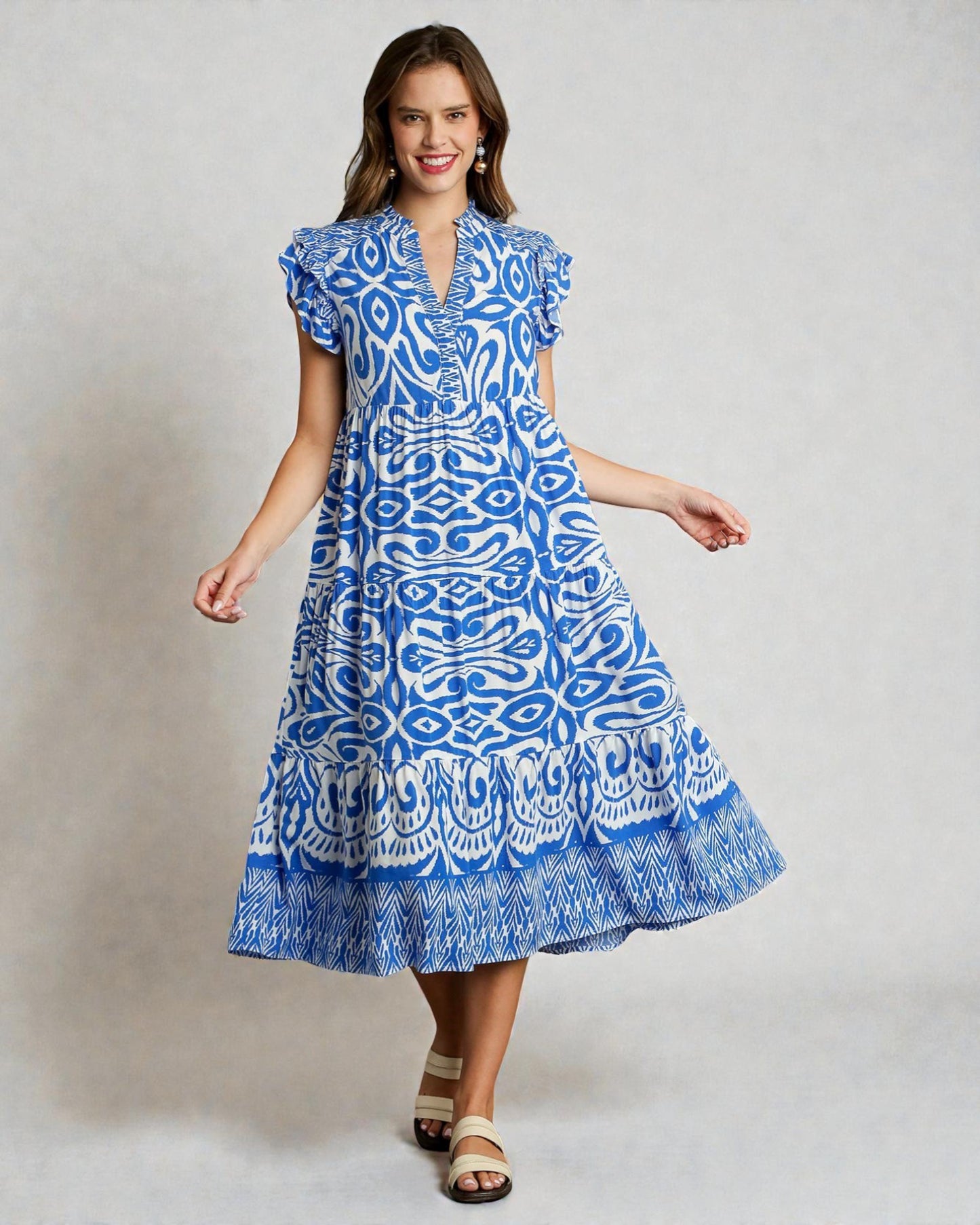 Woman wearing a blue patterned dress on a plain background