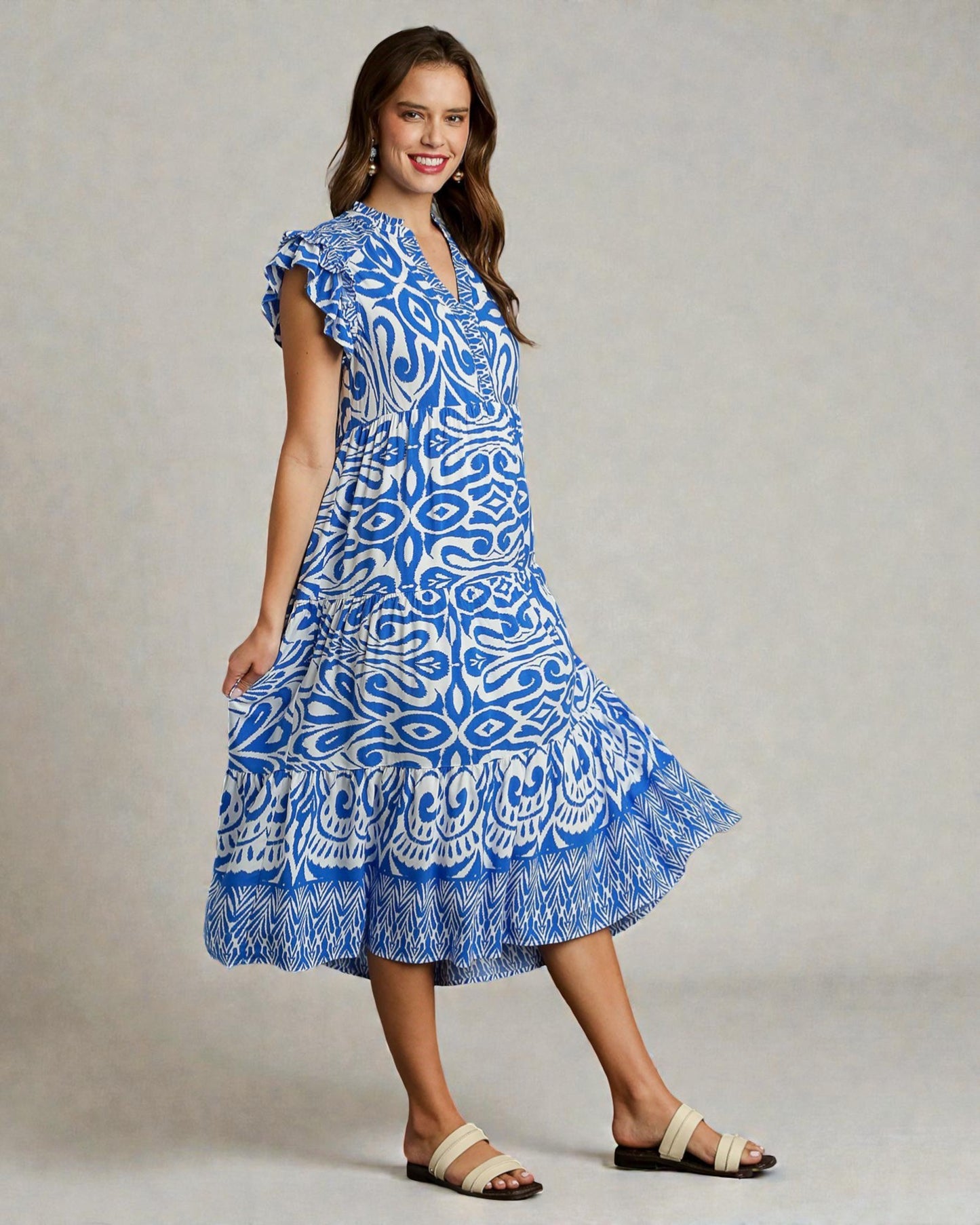 Woman wearing a blue patterned dress on a plain background