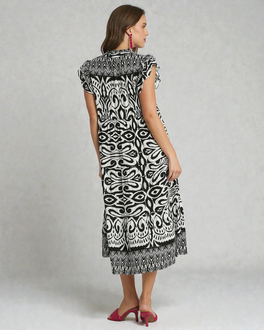 Woman wearing a black and white patterned dress on a gray background