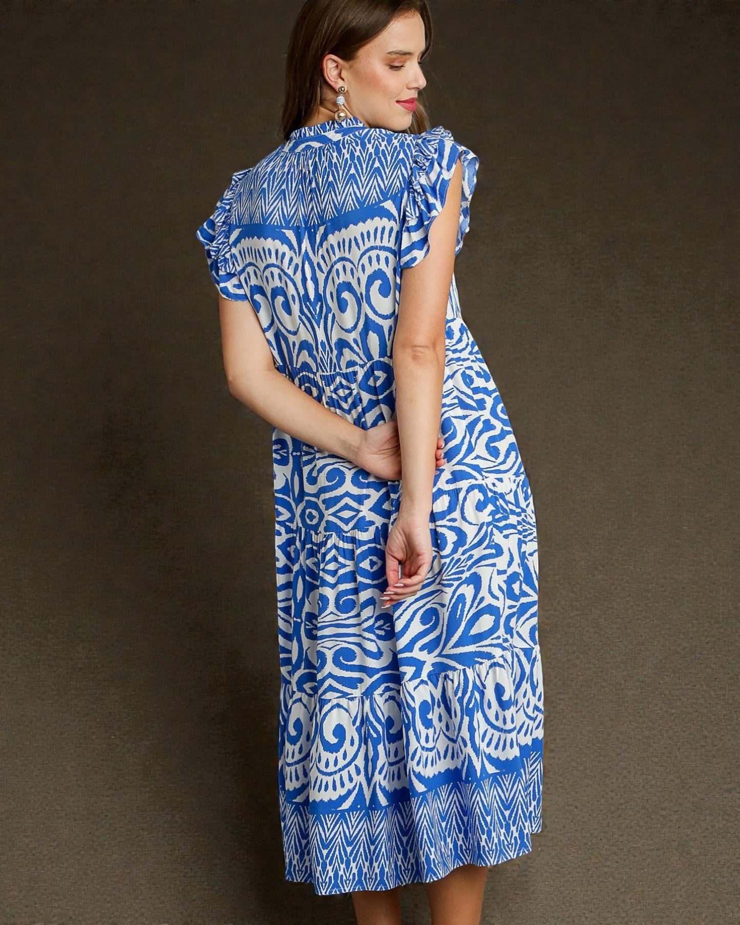 Woman wearing a blue and white patterned dress against a brown background