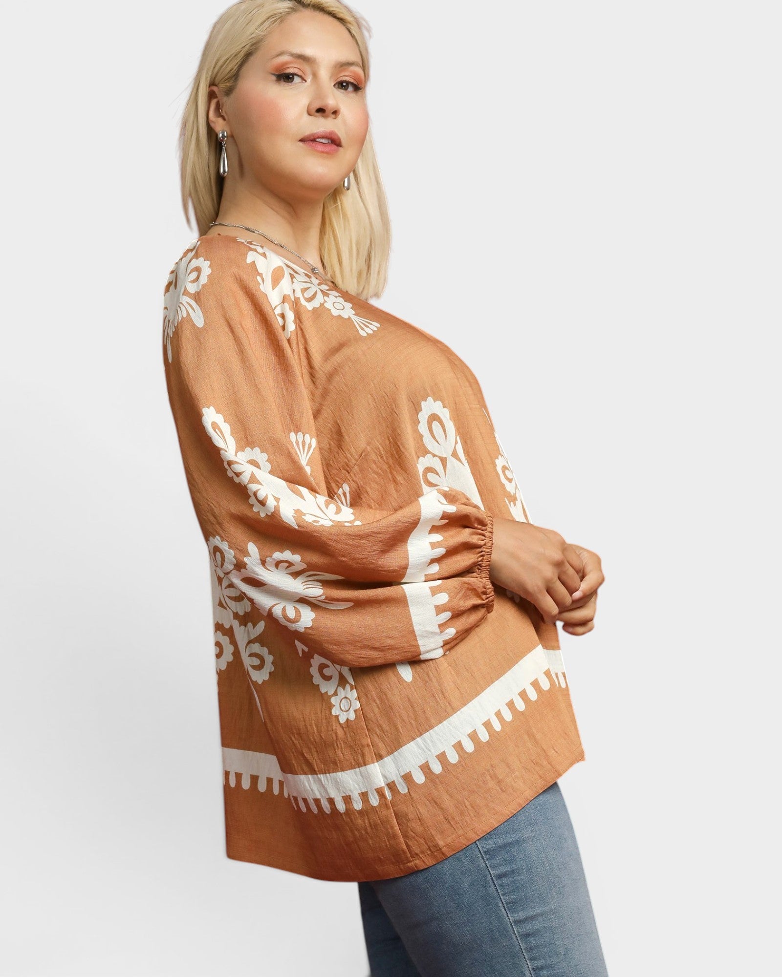 Woman wearing a brown top with white lace details on a white background