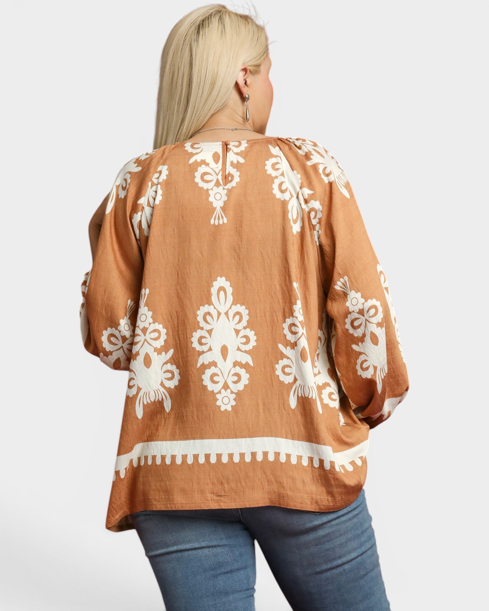 Brown top with white lace patterns worn by a person on a plain background