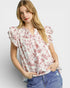 Woman wearing a floral blouse with ruffled sleeves on a plain background
