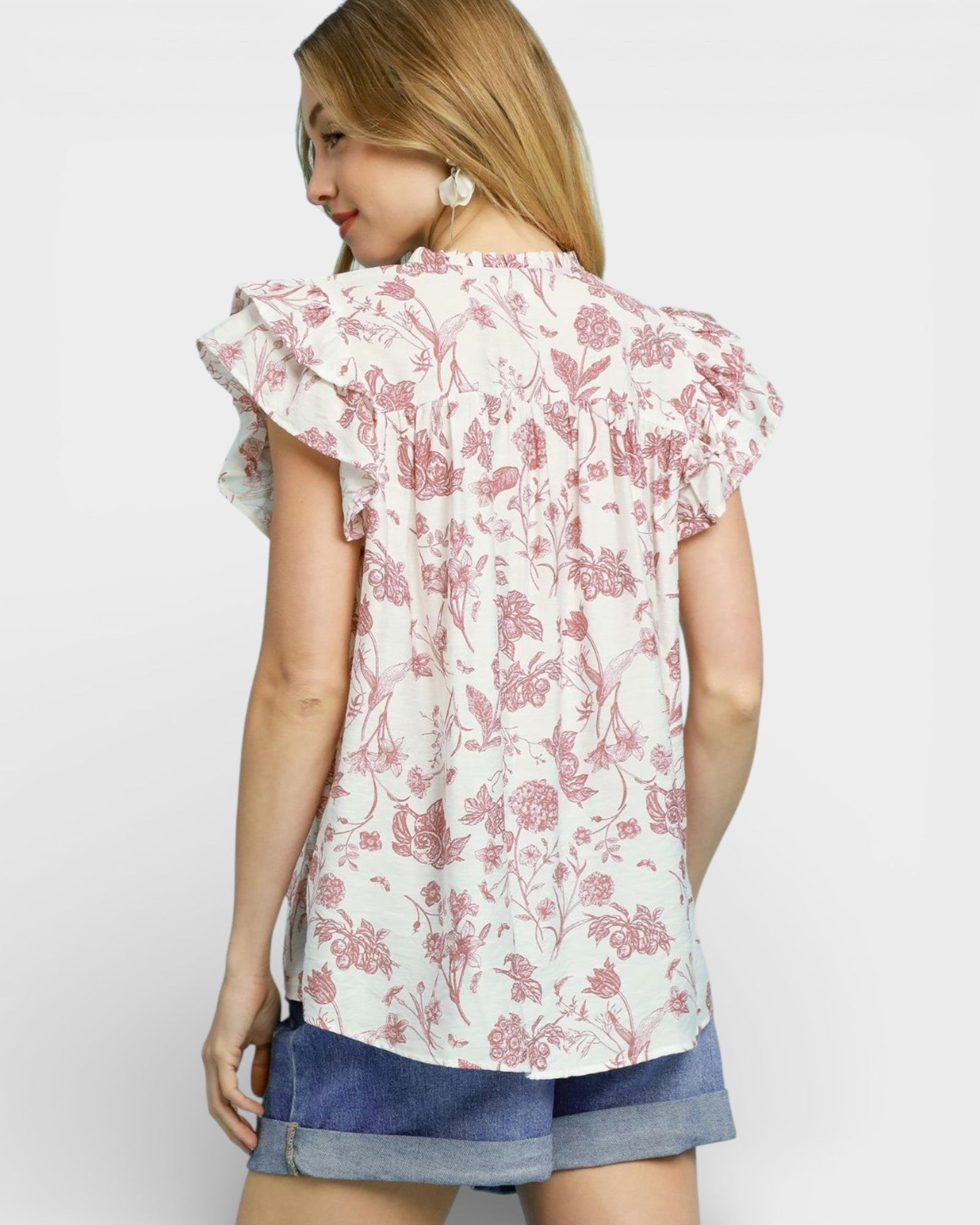 Woman wearing a floral blouse with ruffled sleeves on a white background