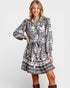 Woman wearing a black and white patterned dress on a plain background