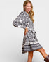 Woman wearing a black and white patterned dress on a plain background