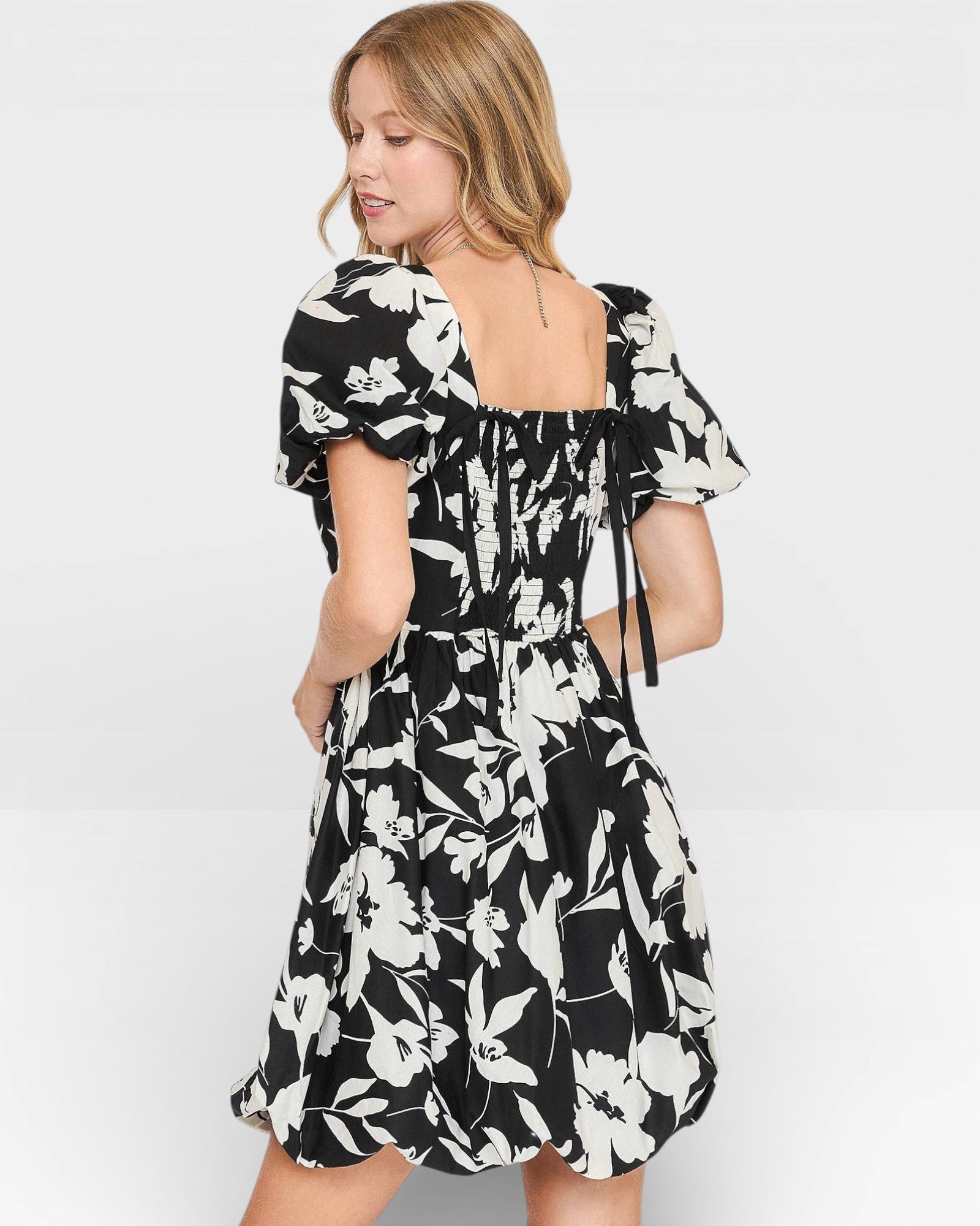 Woman wearing a black and white floral dress on a light gray background