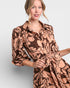 Woman wearing a brown floral patterned dress on a light gray background