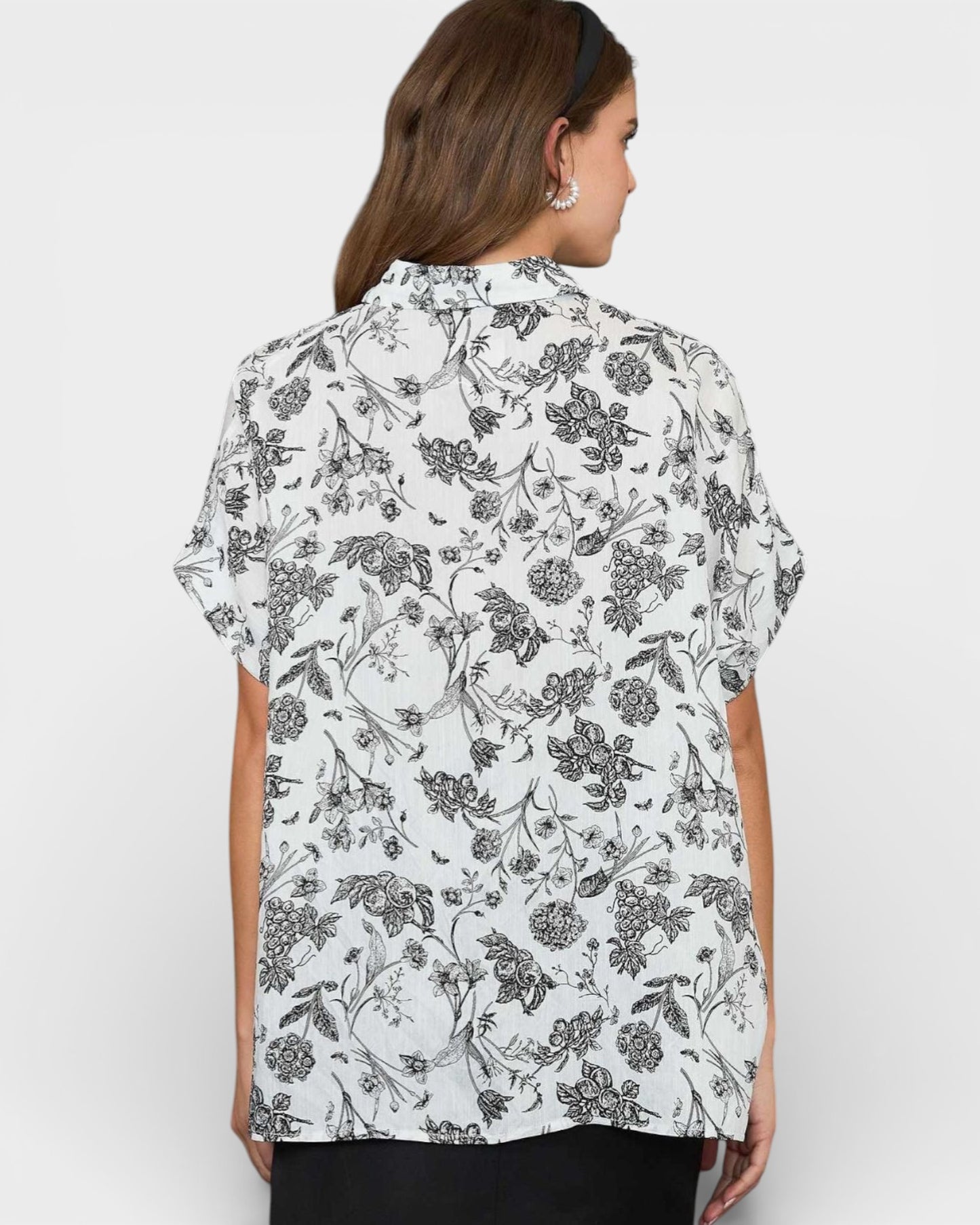 Woman wearing a white floral blouse against a plain background