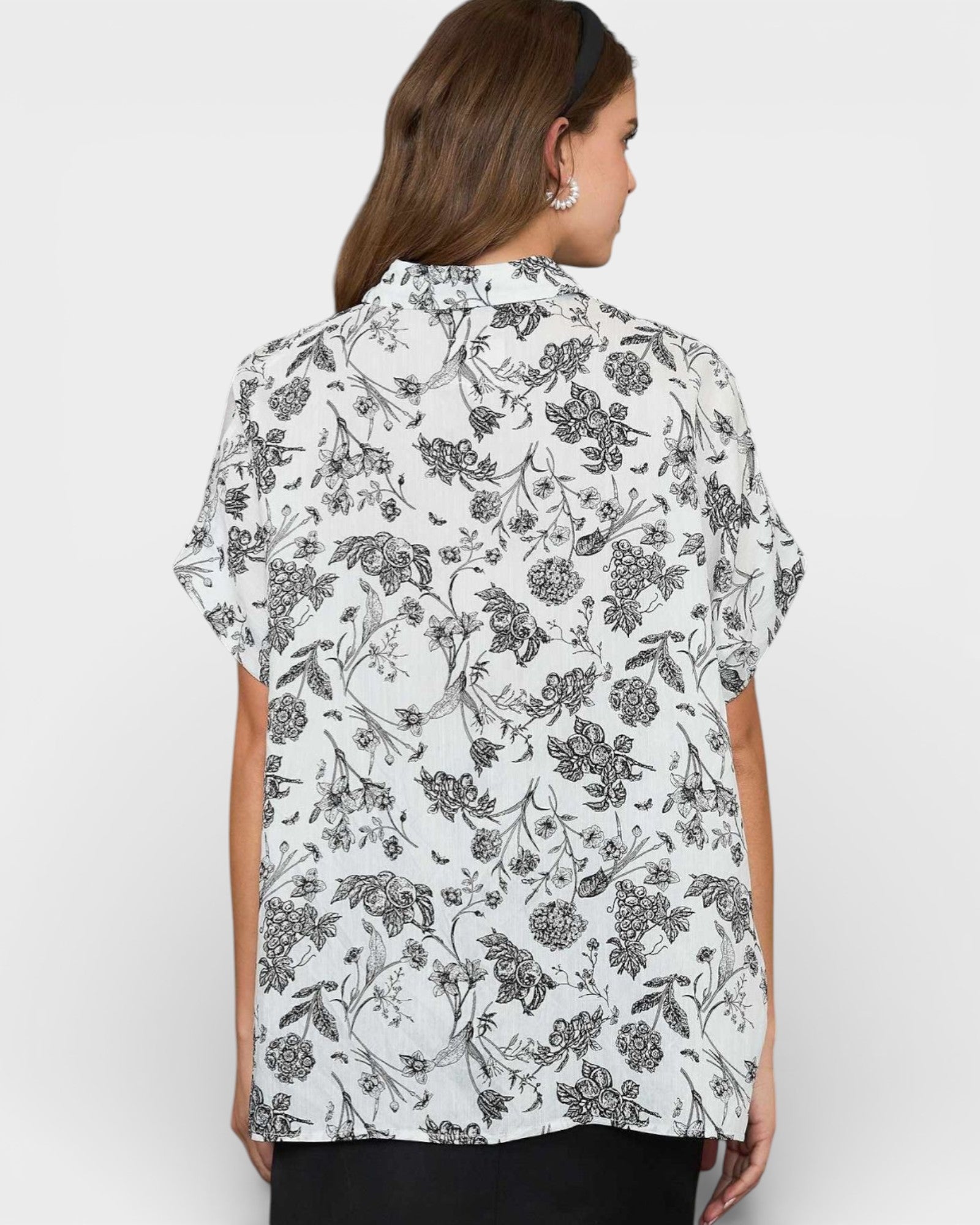 Woman wearing a white floral blouse against a plain background