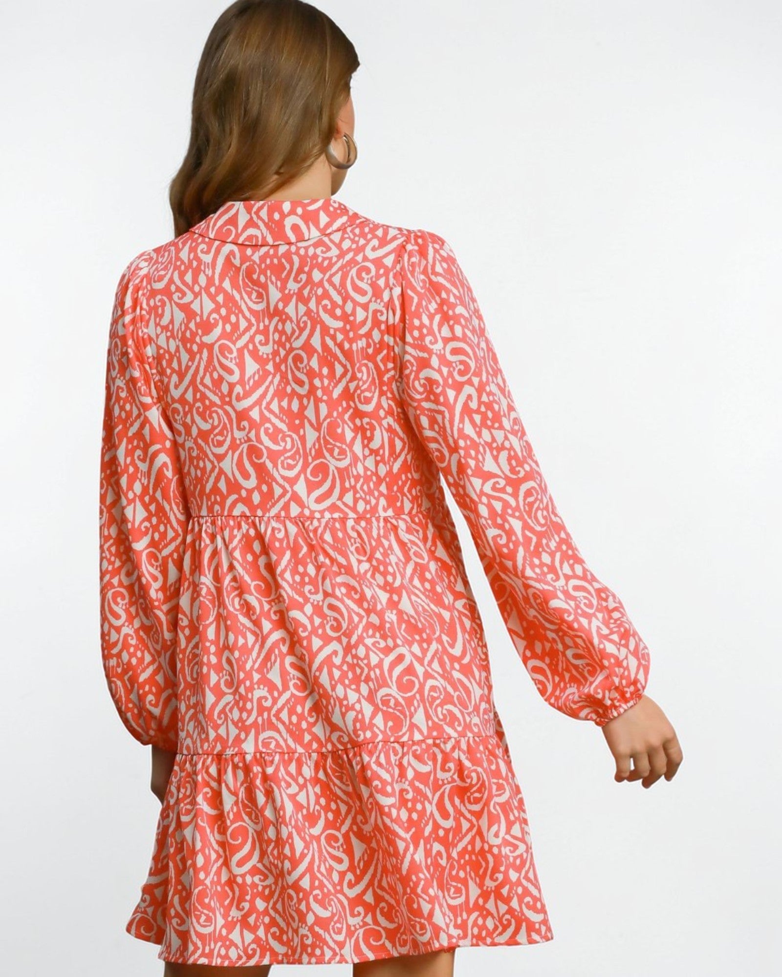 Woman wearing a coral patterned dress on a white background
