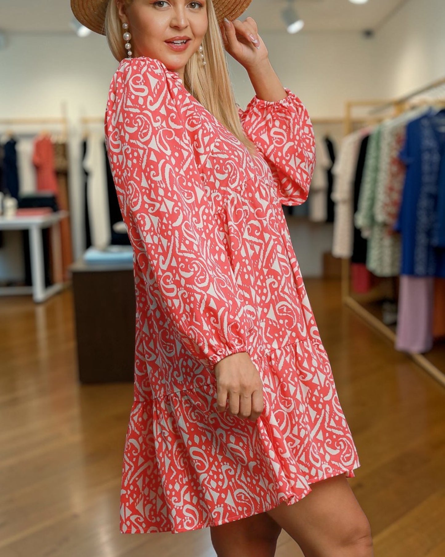 Woman wearing a red patterned dress in a clothing store