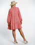 Person wearing a red patterned dress and straw hat on a white background