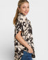 Woman wearing a patterned shirt with a plain background