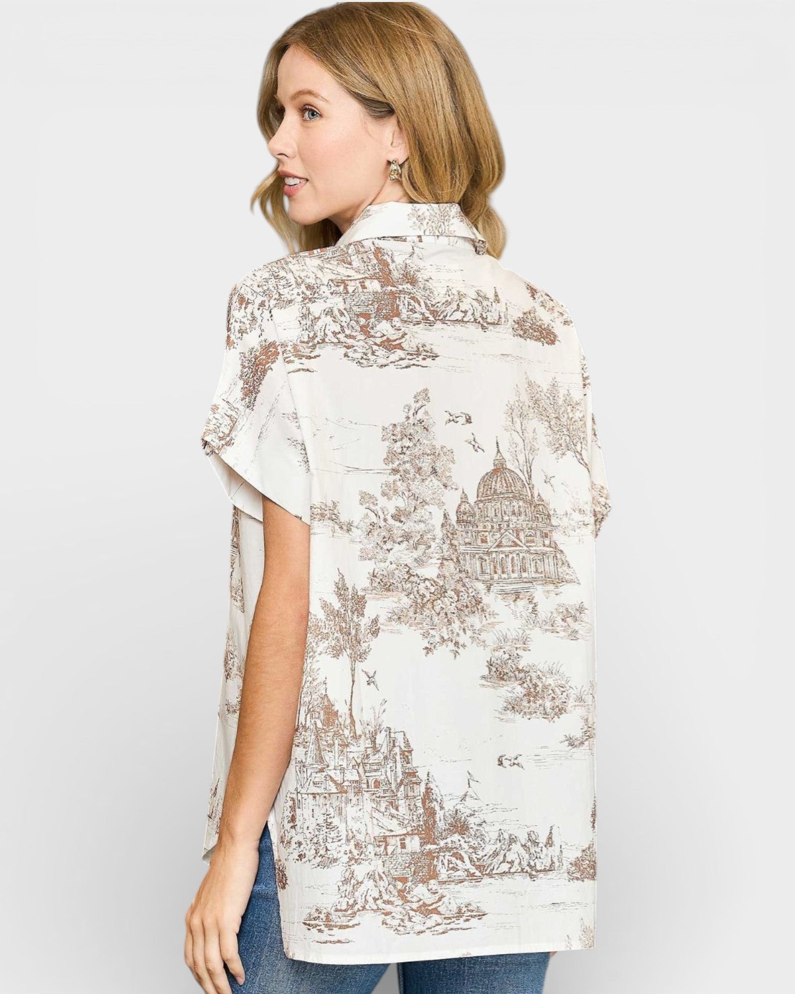 Woman wearing a white blouse with brown pattern on a plain background