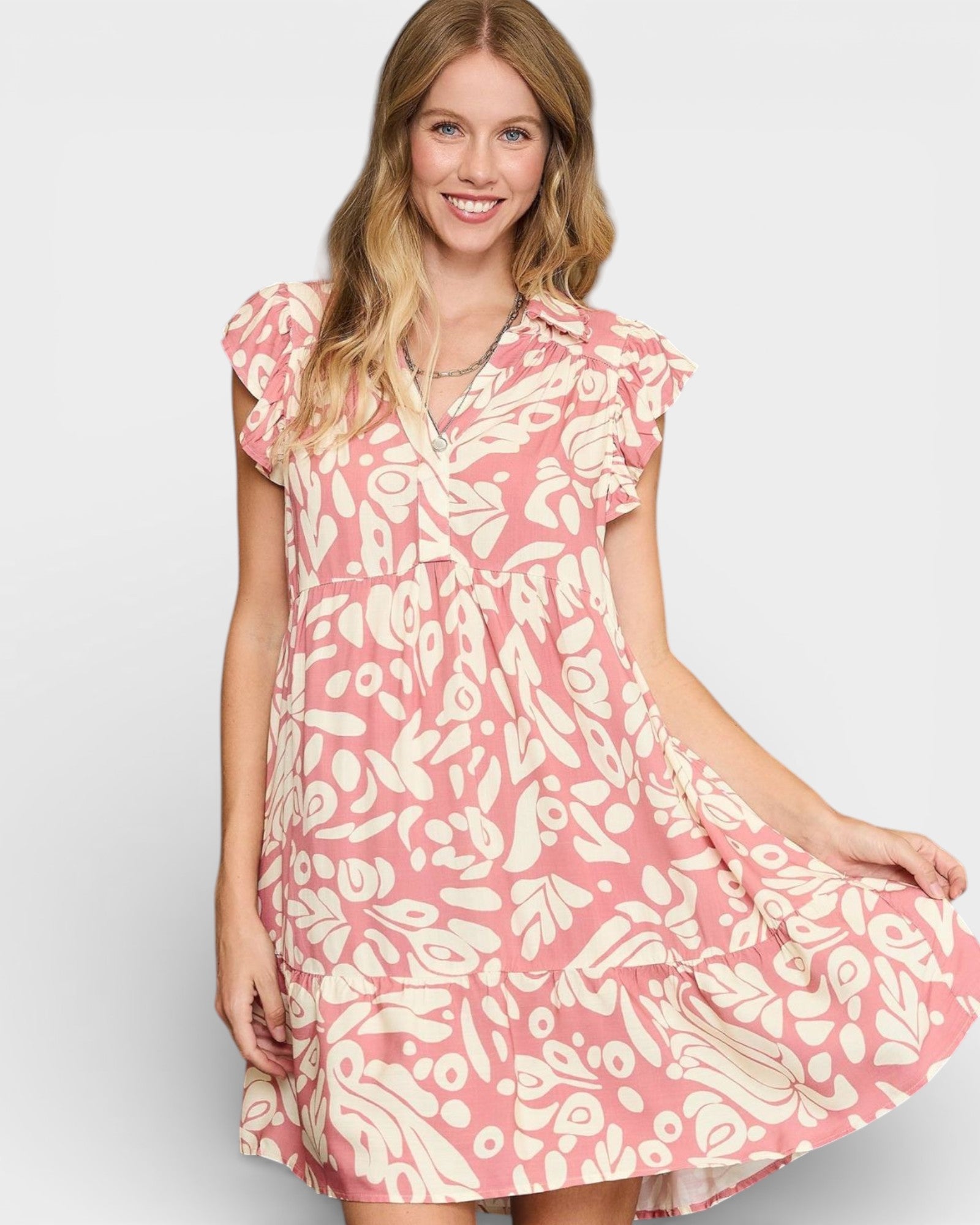 Woman wearing a pink and white patterned dress on a plain background