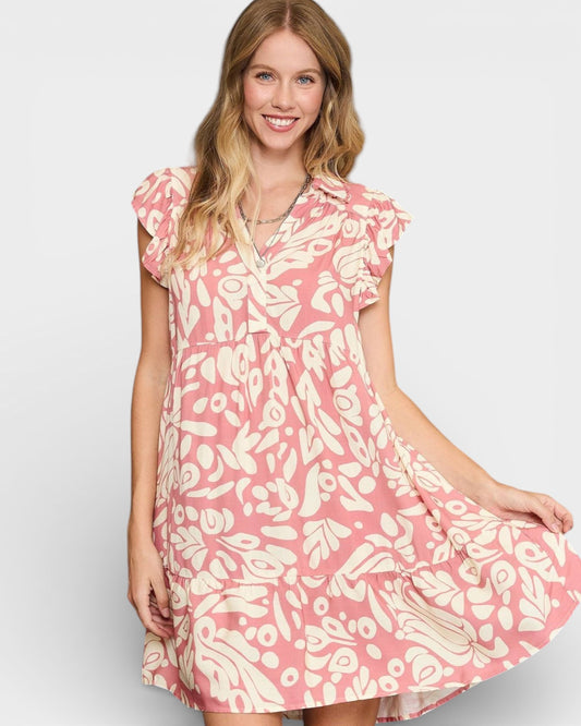 Woman wearing a pink and white patterned dress on a plain background