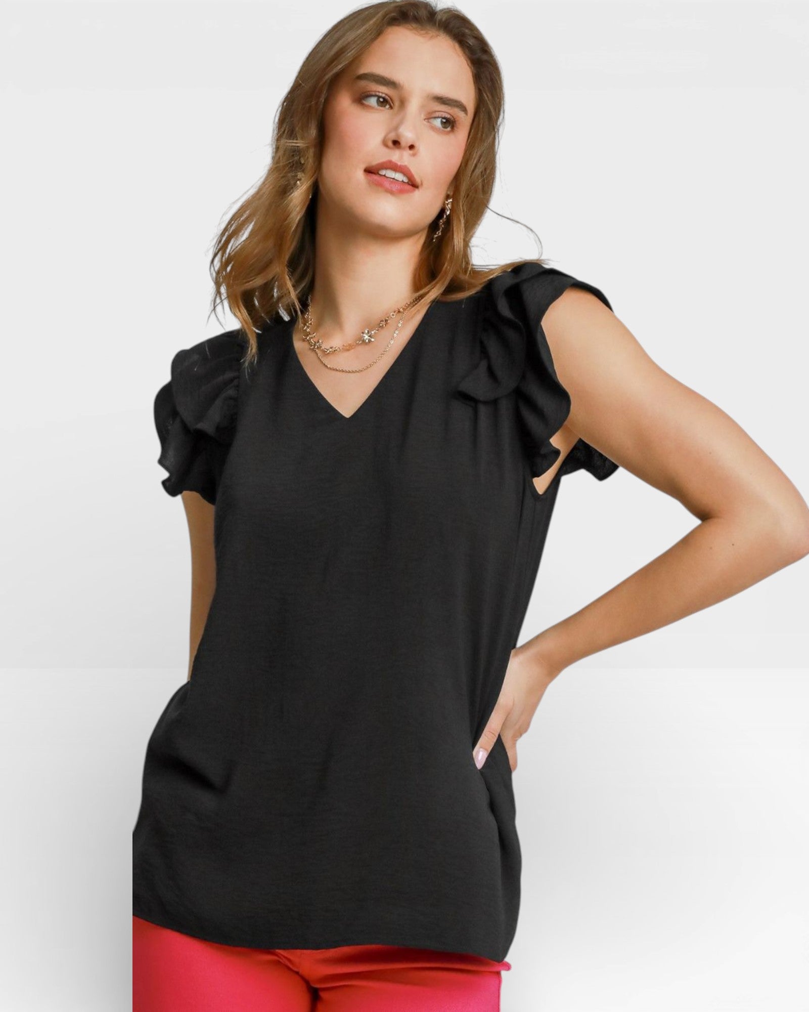 Woman wearing a black sleeveless top with ruffled shoulders on a white background