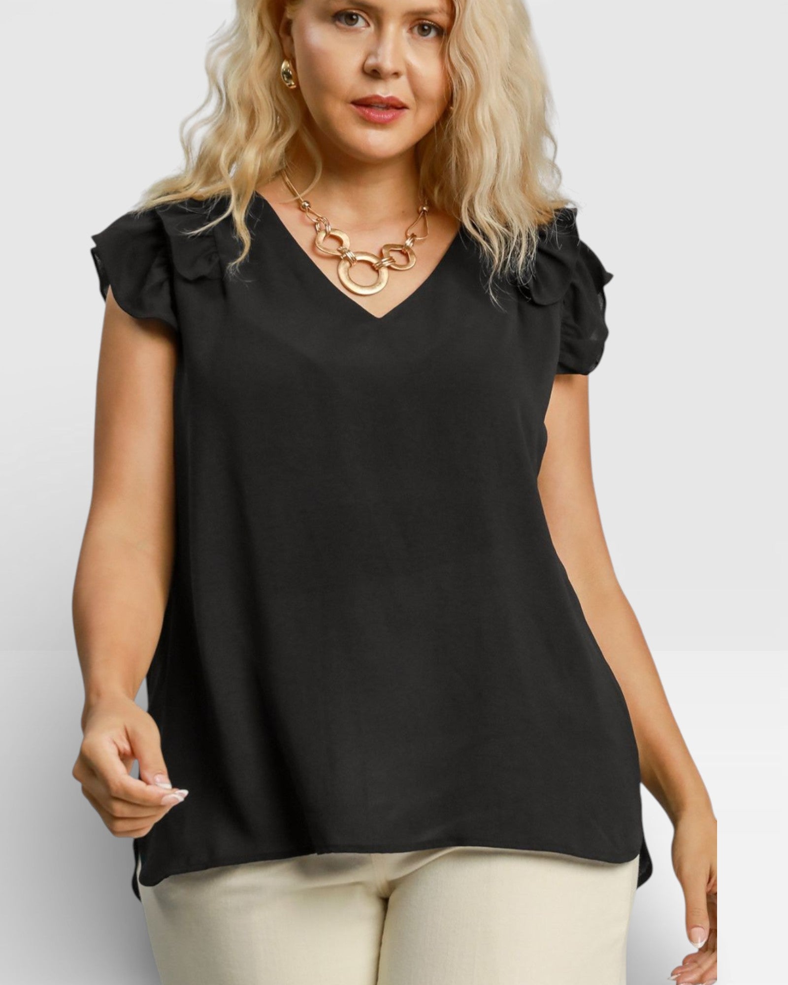 Woman wearing a black blouse with ruffled shoulders on a white background