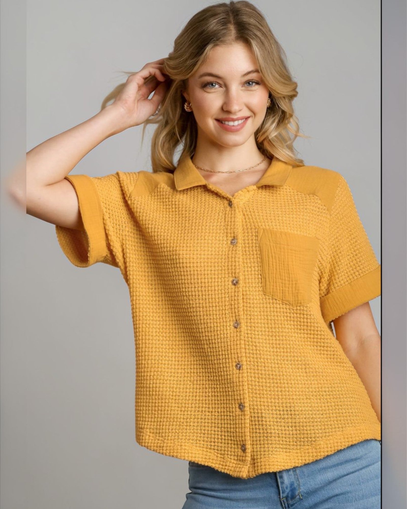 Woman wearing a mustard yellow textured shirt against a gray background