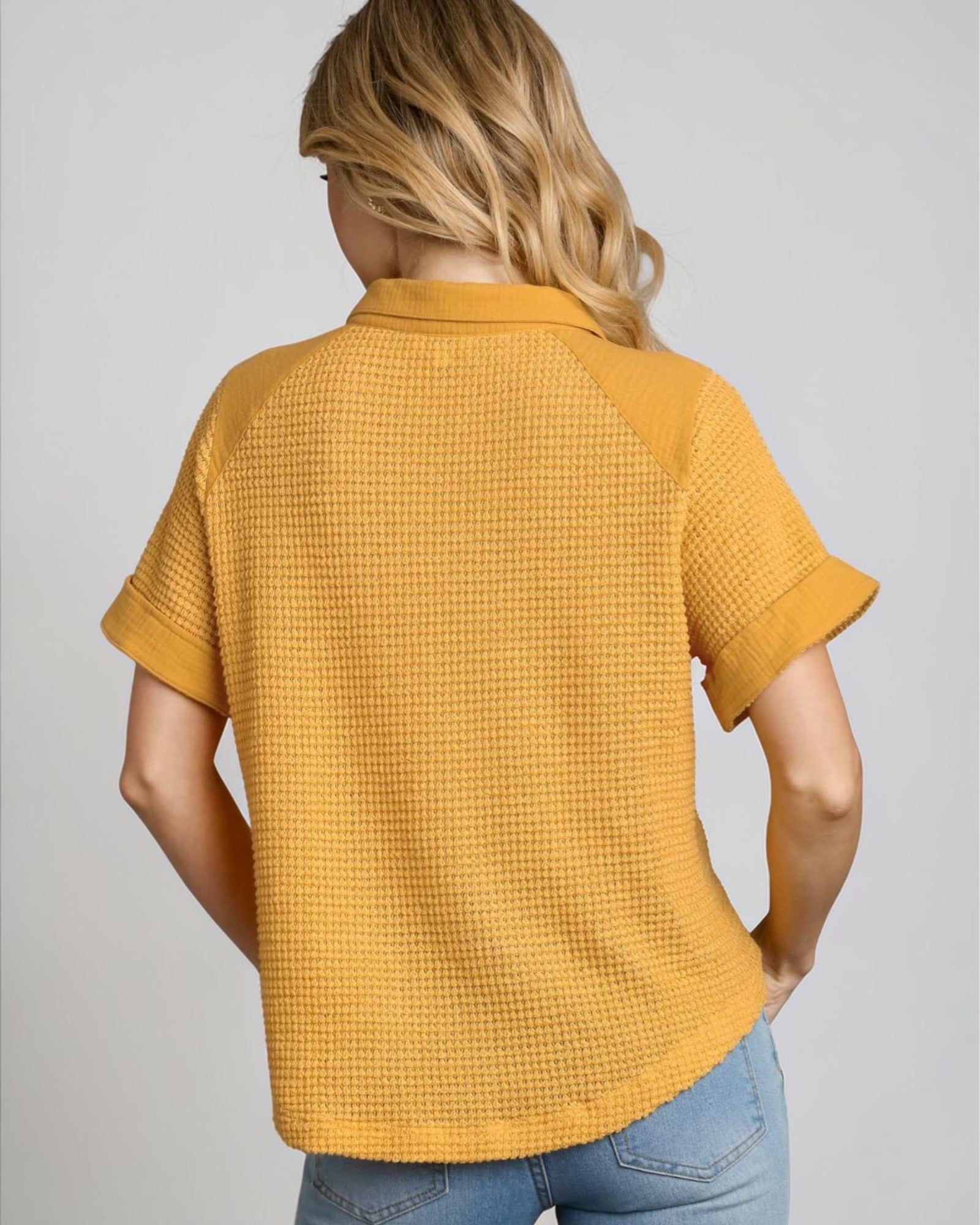 Person wearing a mustard yellow textured shirt on a plain background