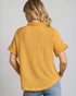 Person wearing a mustard yellow textured shirt on a plain background