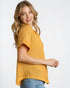 Woman wearing a yellow textured top and blue jeans on a white background