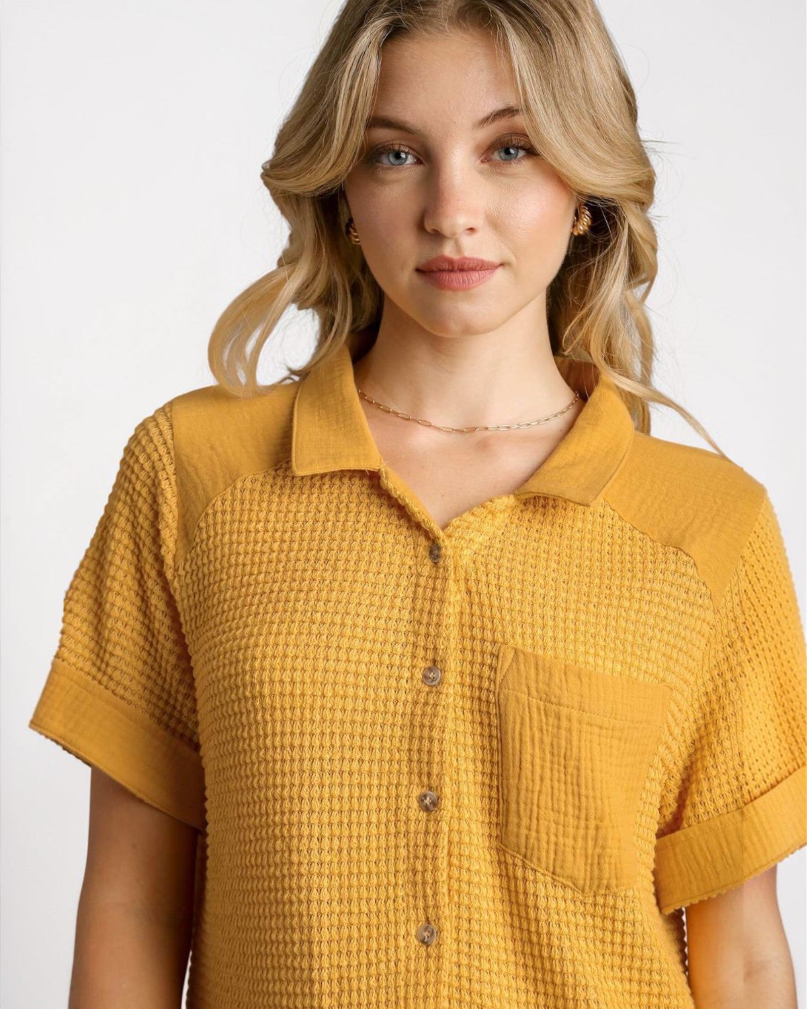 Woman wearing a mustard yellow textured shirt against a white background
