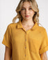 Woman wearing a mustard yellow textured shirt against a white background