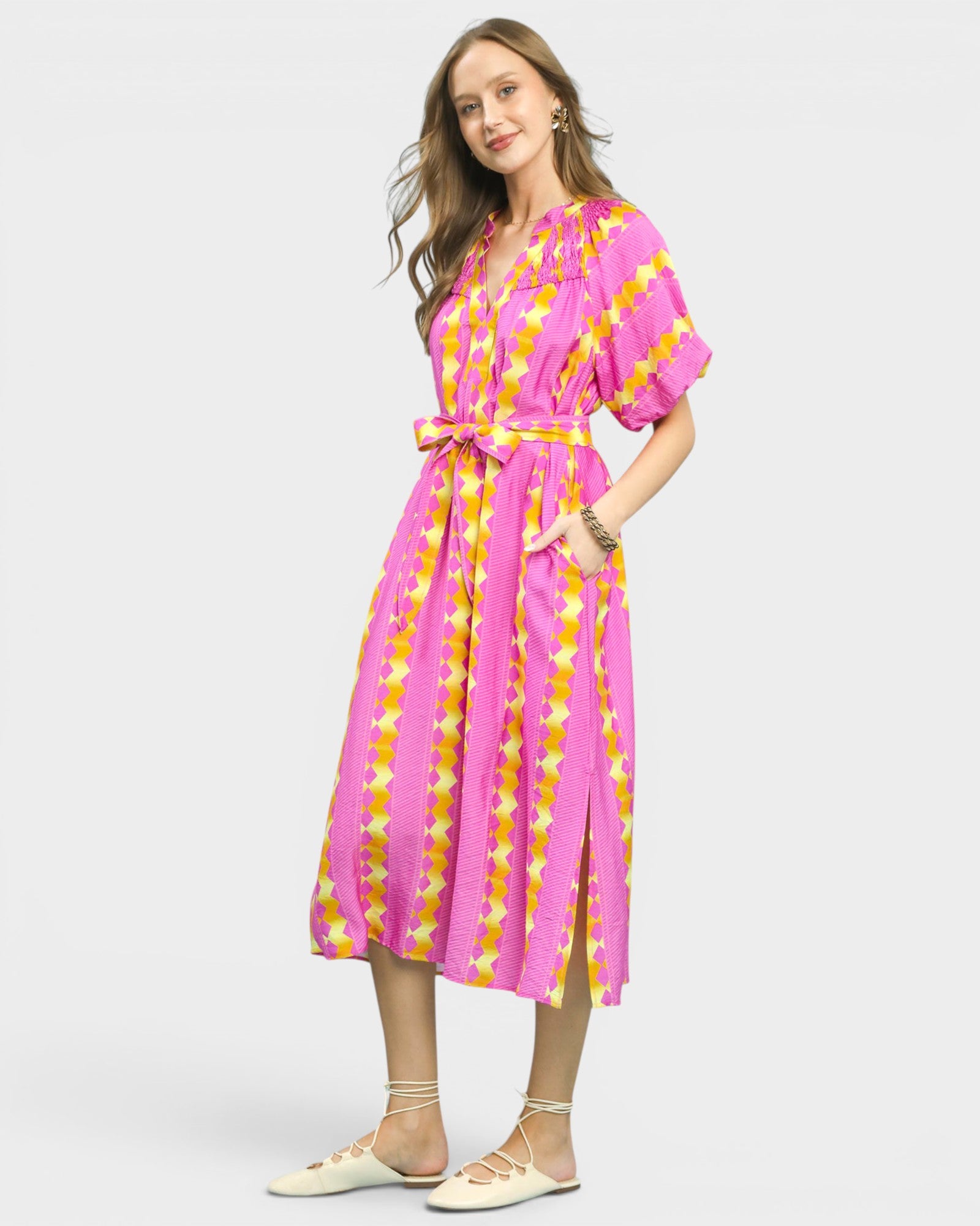 Woman wearing a pink and yellow patterned dress on a white background