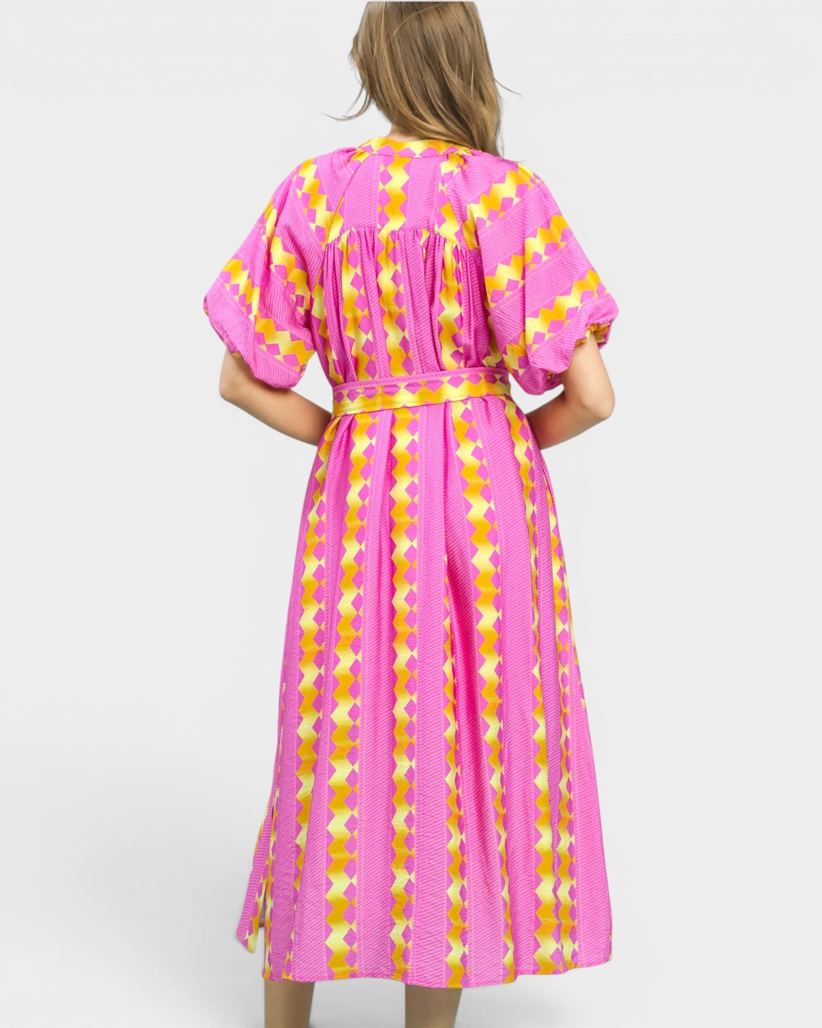Woman wearing a pink and yellow patterned dress on a white background