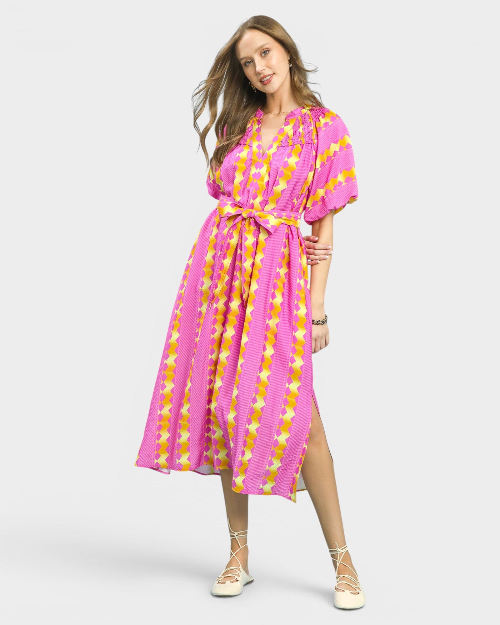 Woman wearing a pink and yellow tie-dye dress on a white background