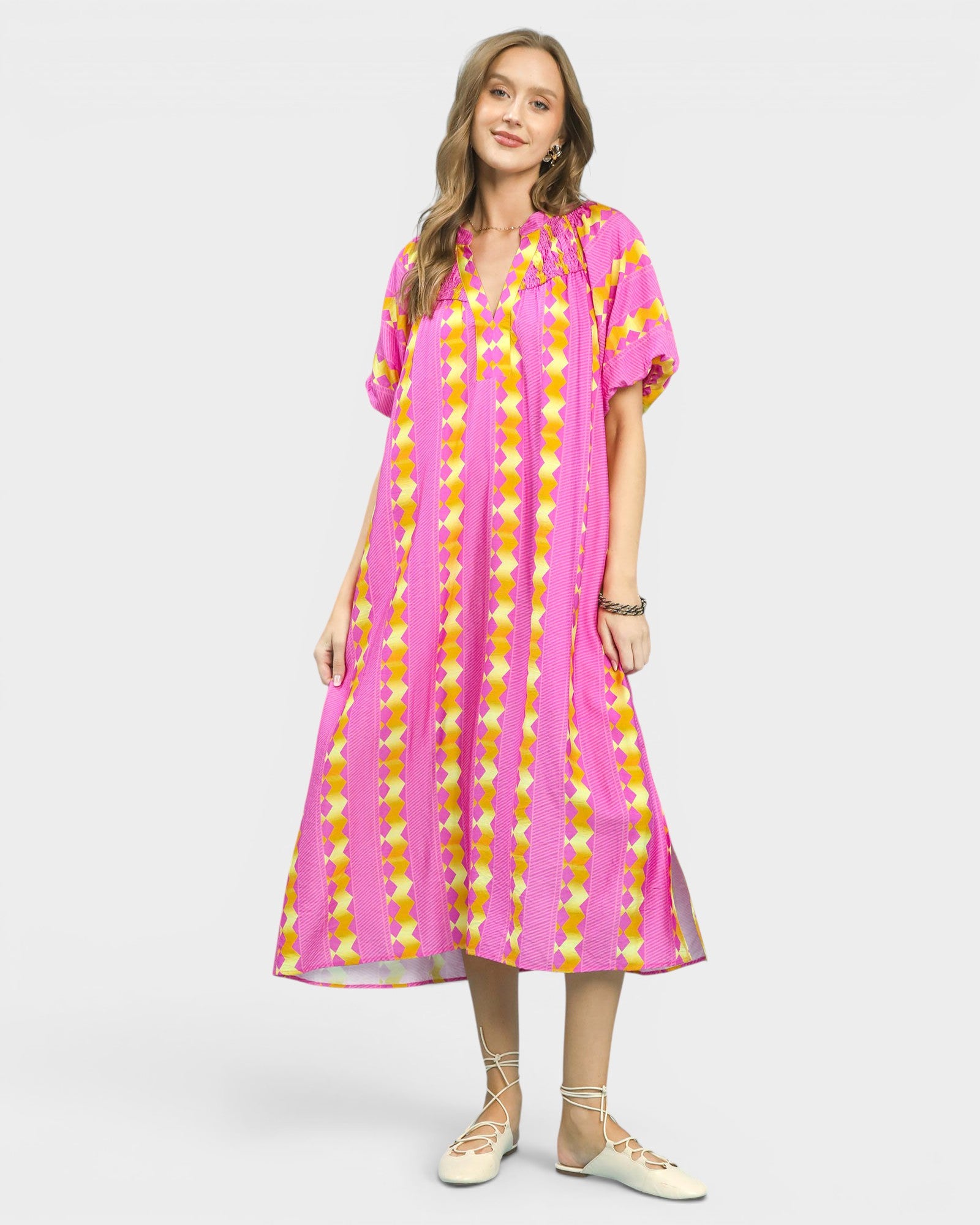 Woman wearing a pink and yellow patterned dress on a white background