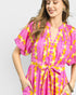 Woman wearing a pink and yellow patterned dress on a light gray background