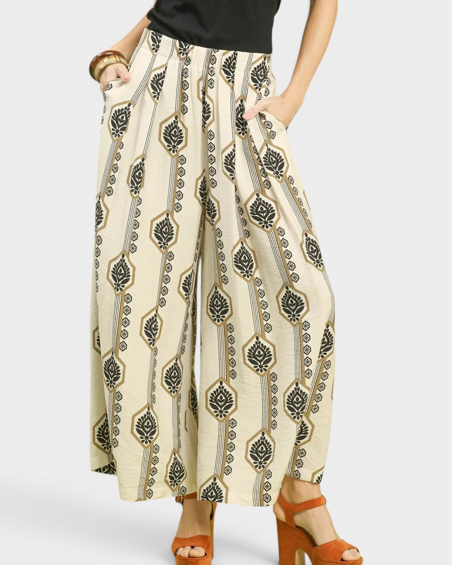 Beige pants with black geometric pattern worn by a person on a white background
