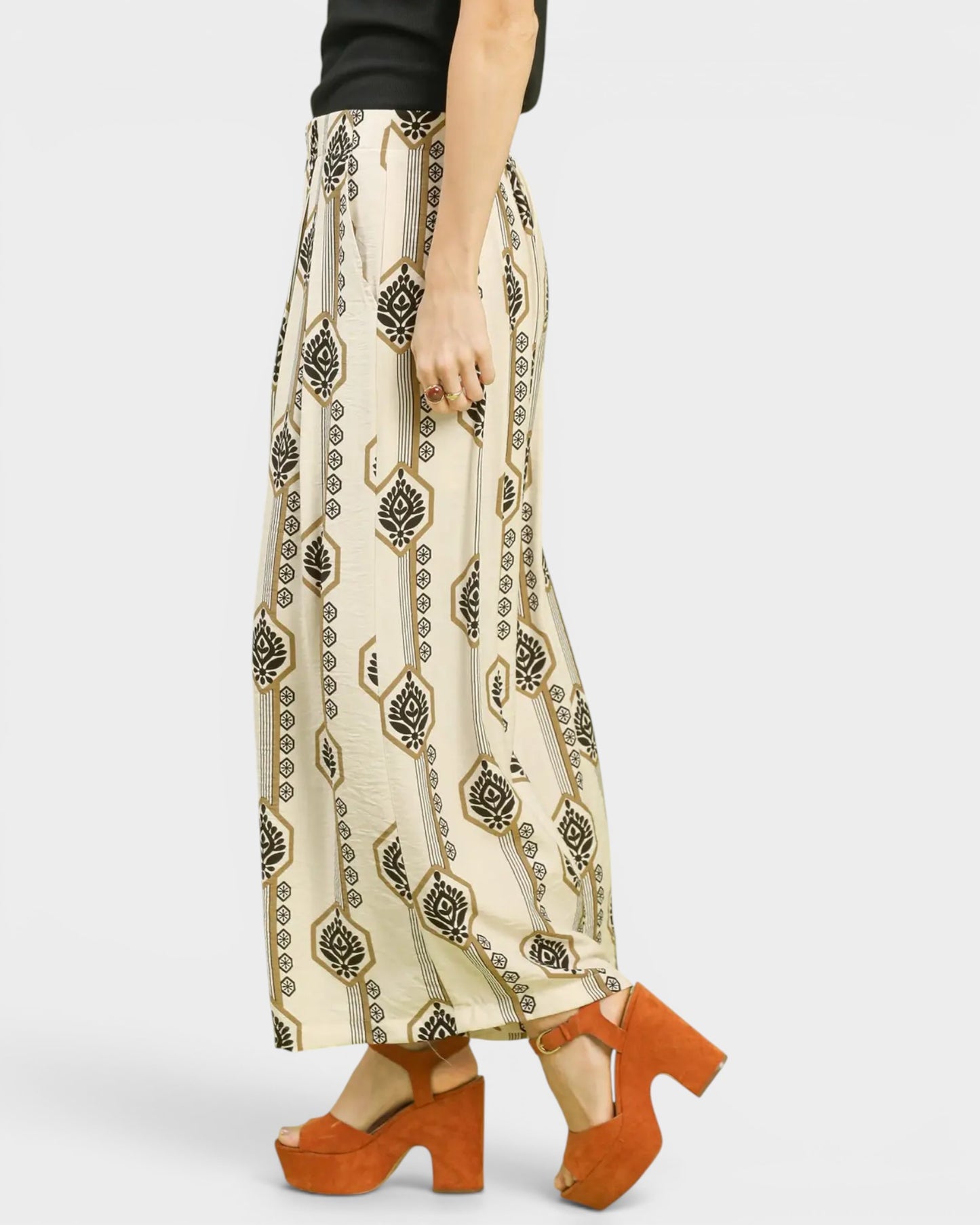 Person wearing a patterned skirt and orange shoes on a white background