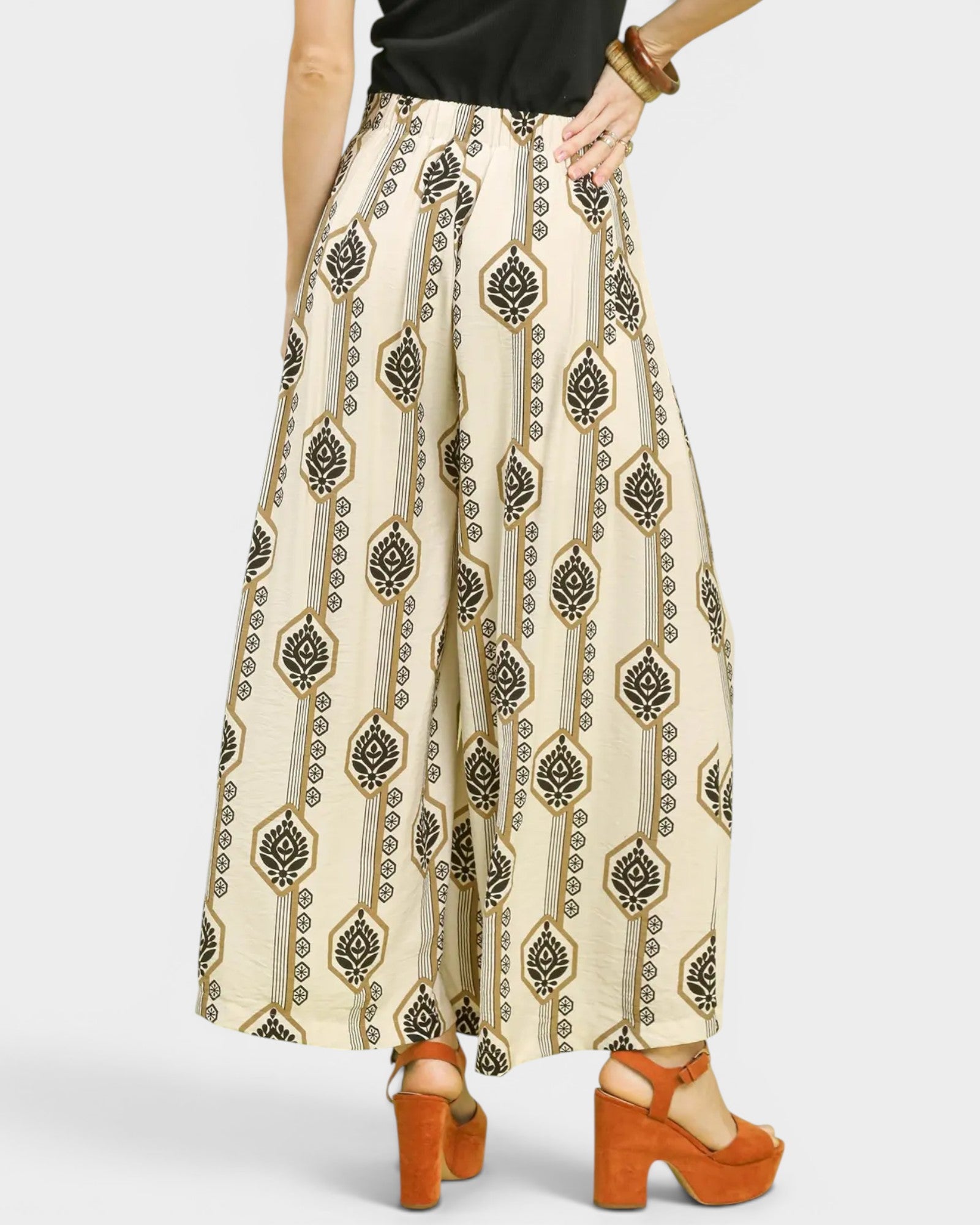 Person wearing a patterned skirt with orange shoes on a white background