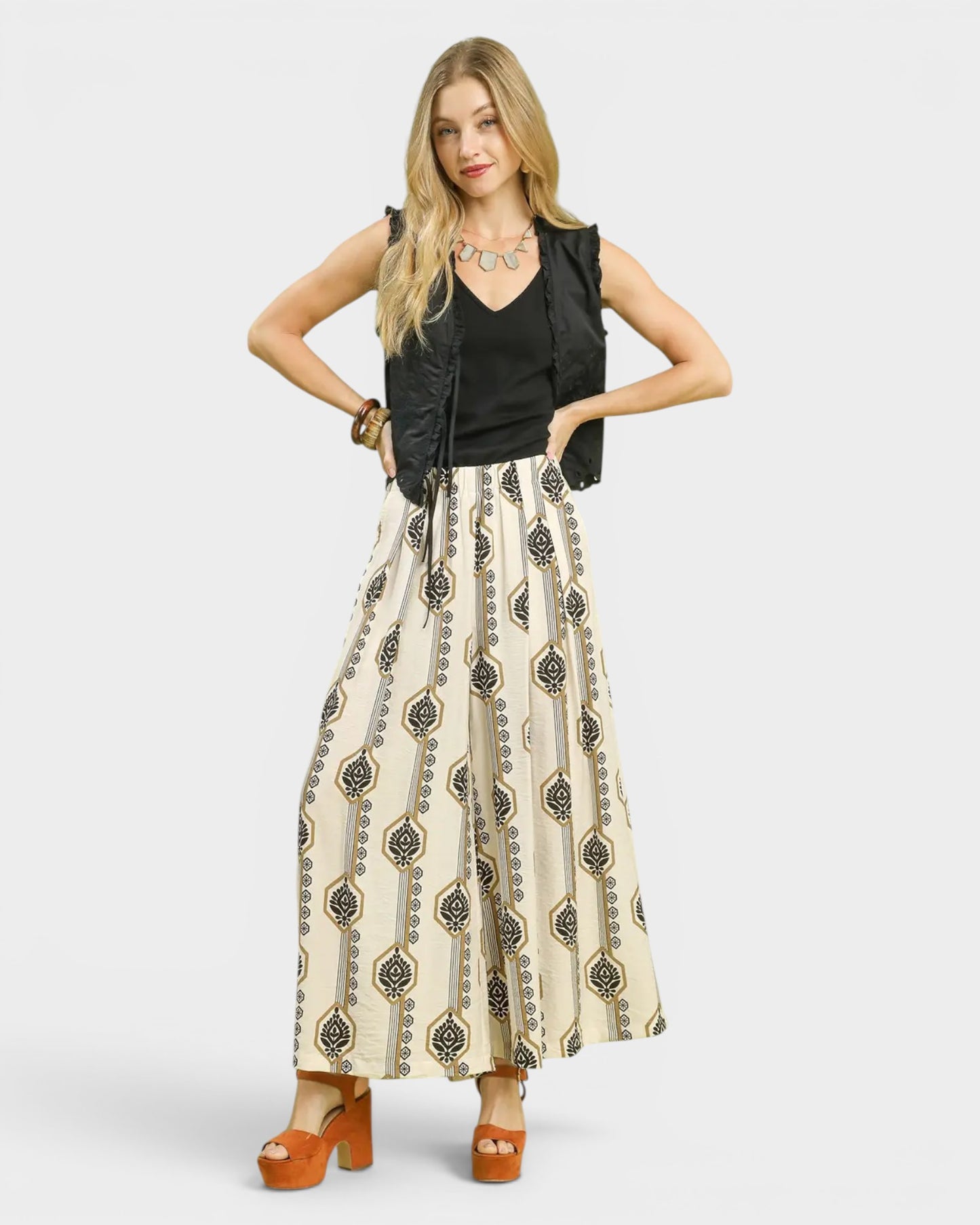 Woman wearing a black sleeveless top and patterned skirt on a white background