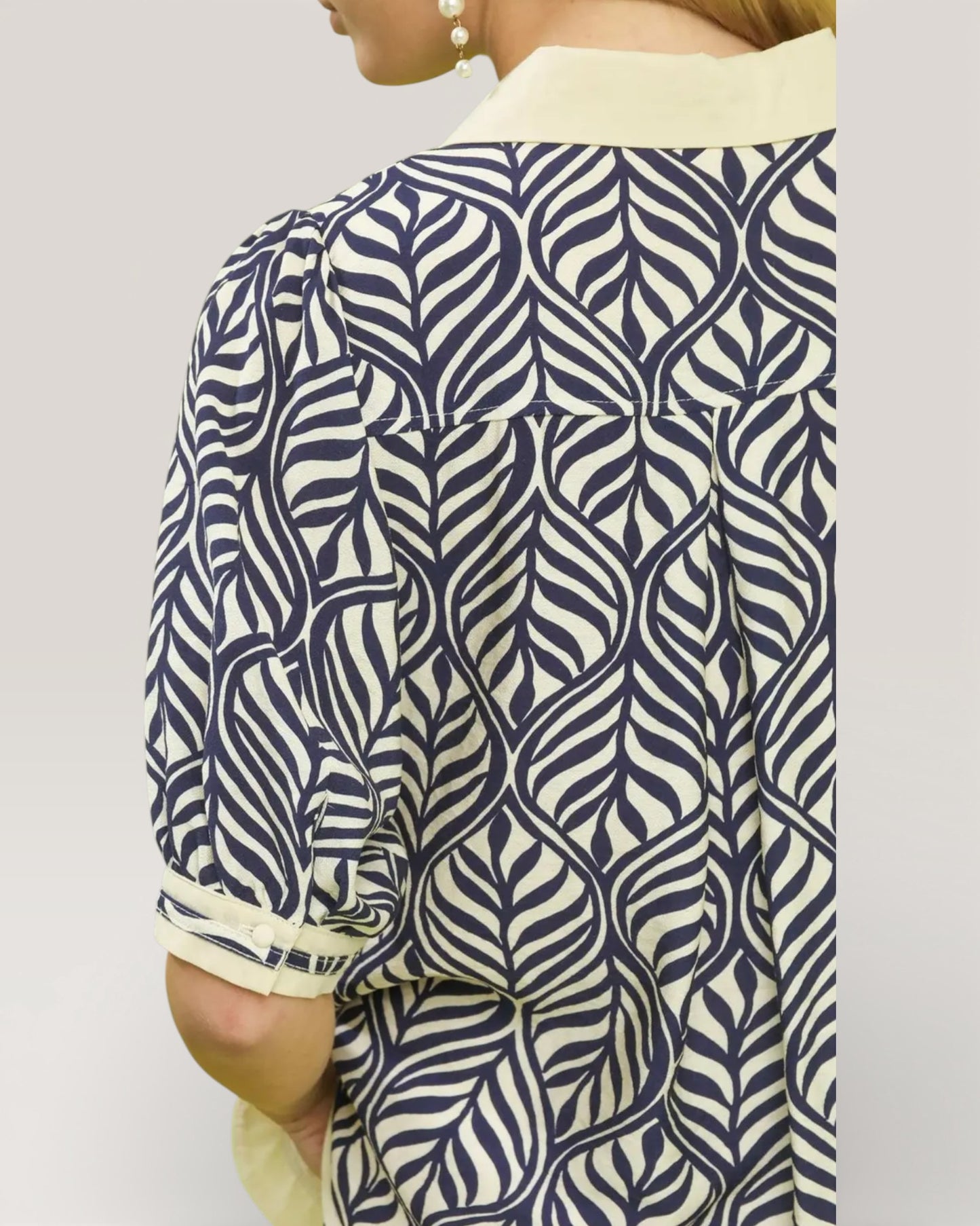 Person wearing a blue and white patterned shirt with a plain background