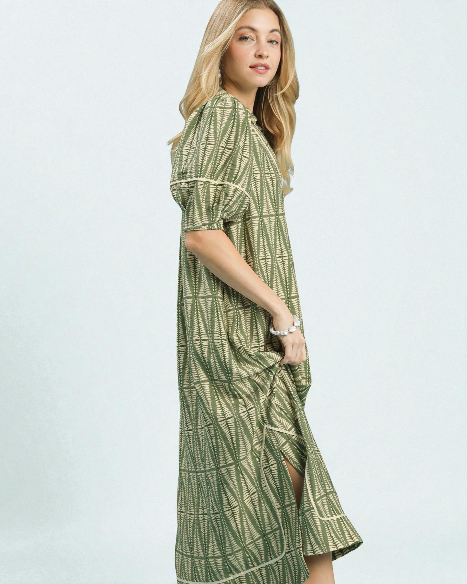 Woman wearing a green patterned dress on a white background