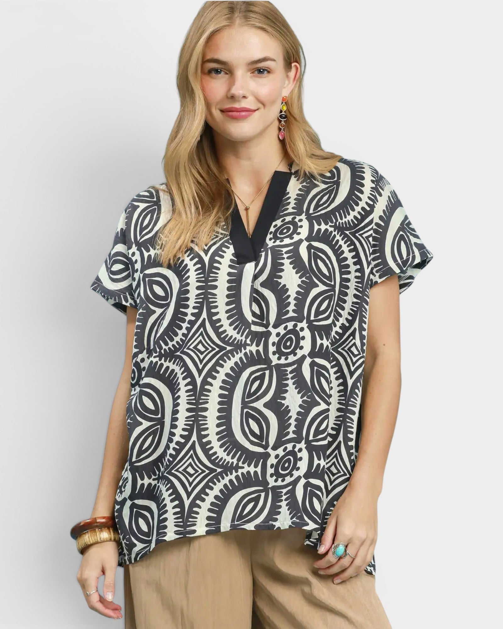 Woman wearing a black and white patterned blouse on a light gray background
