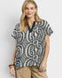 Woman wearing a black and white patterned blouse on a light gray background
