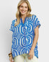 Woman wearing a blue and white patterned top on a plain background
