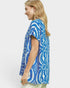 Woman wearing a blue and white patterned shirt on a plain background