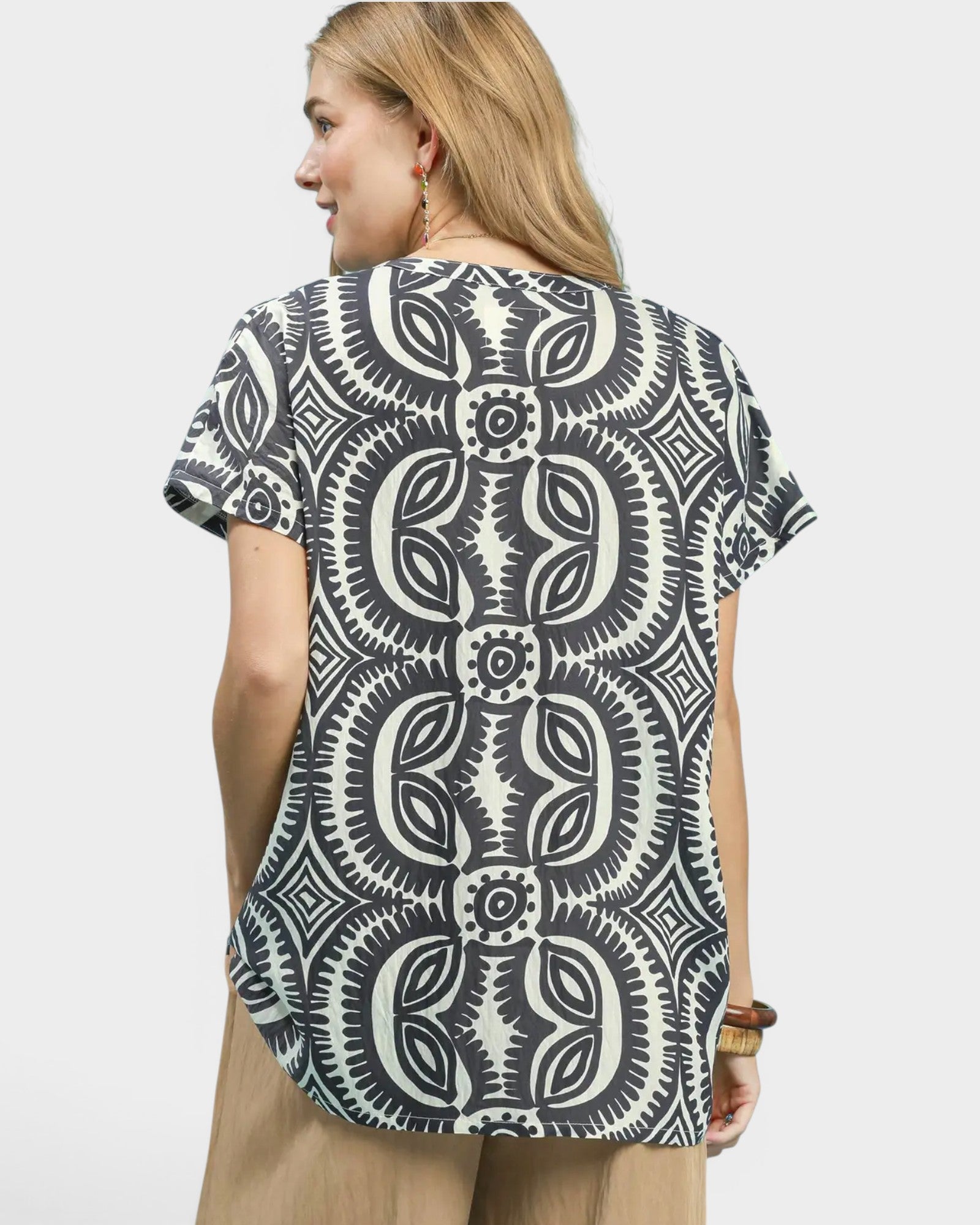 Woman wearing a black and white patterned shirt on a plain background