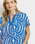 Woman wearing a blue and white patterned dress against a plain background