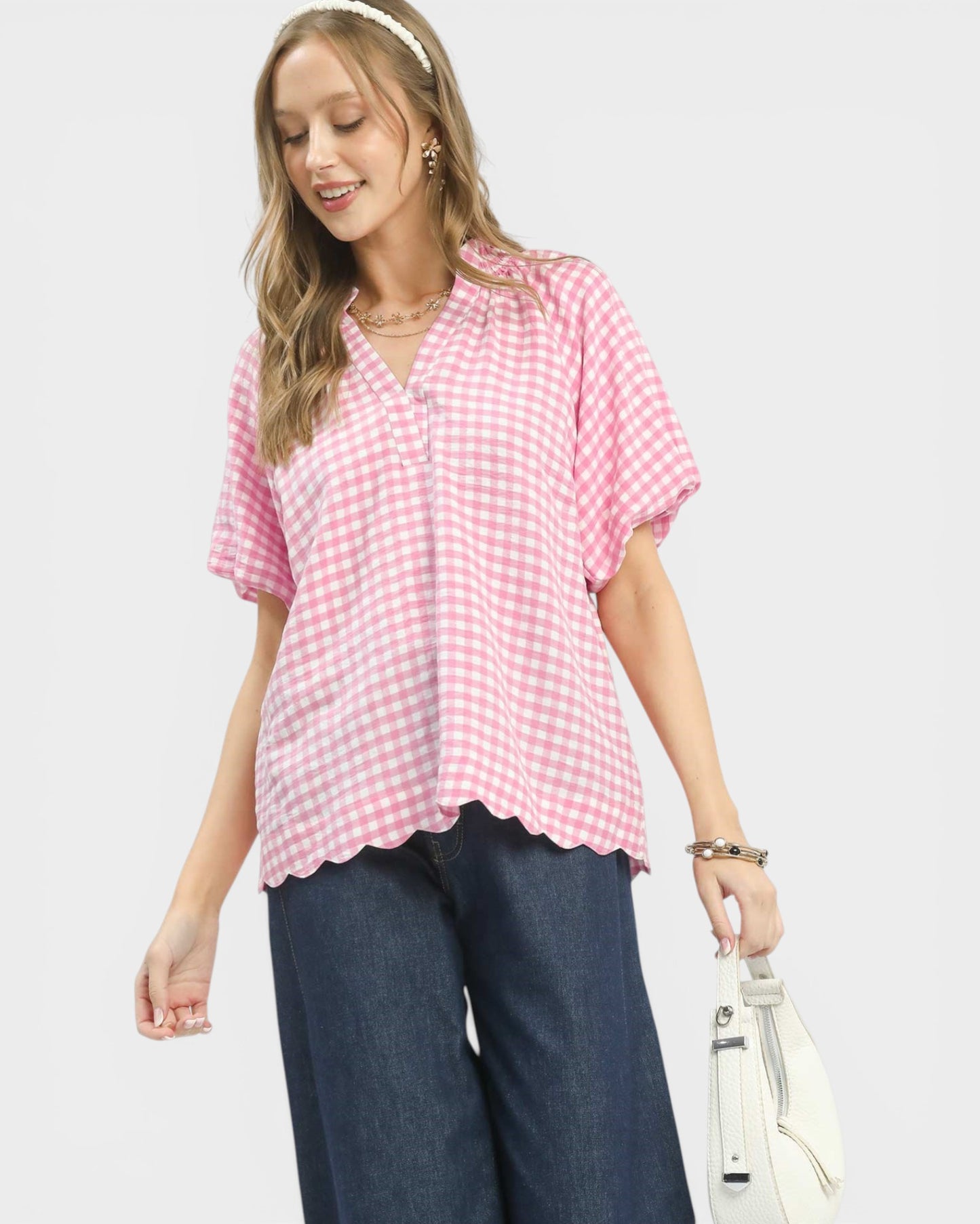 Woman wearing a pink checkered blouse and blue pants on a white background
