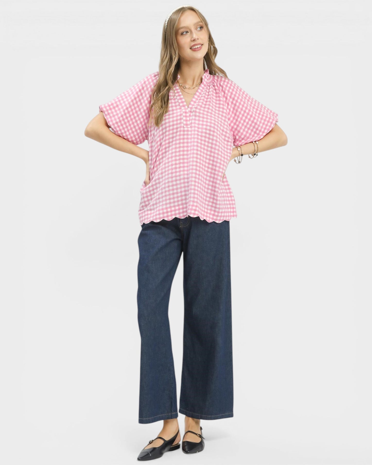 Woman wearing a pink checkered blouse and blue jeans on a white background